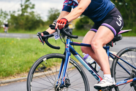 Torso of a woman rounding a steep switchback on her bike.