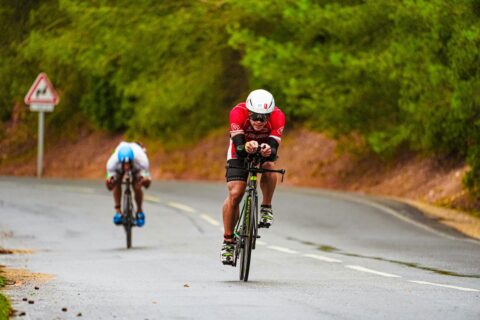 Two cyclists riding downhill and going power
