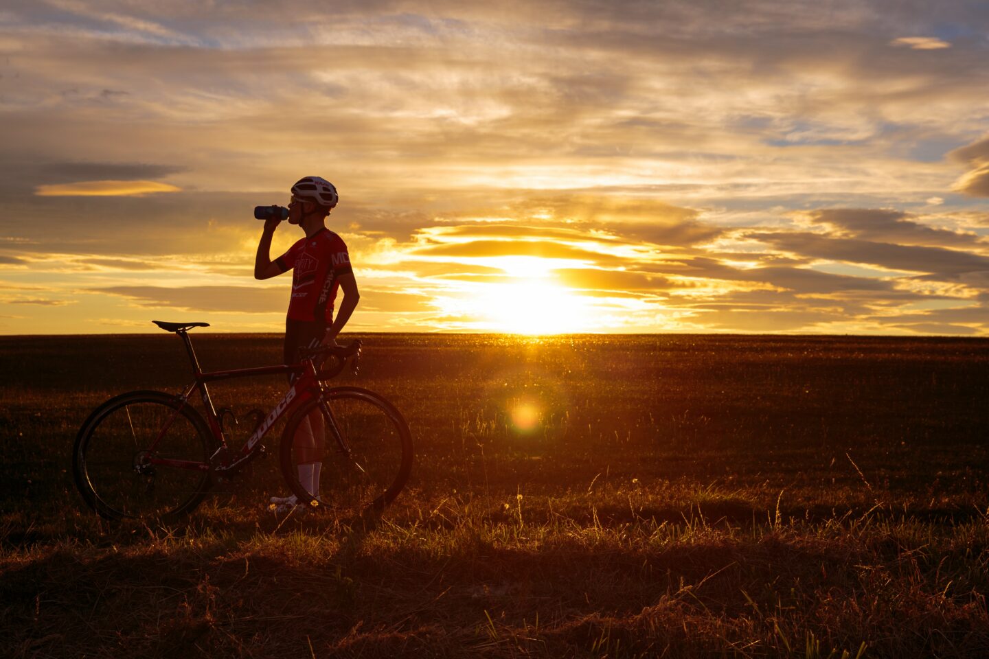 Cyclist Taking Water Break in Front of Sunset