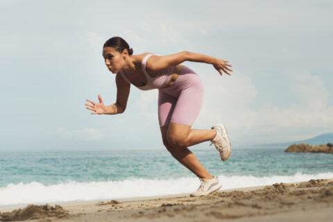 Woman doing running drills on a beach for importance of adaptations