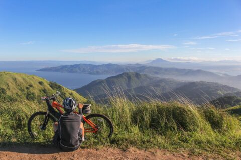 Cyclist resting at top of lookout point next to bike