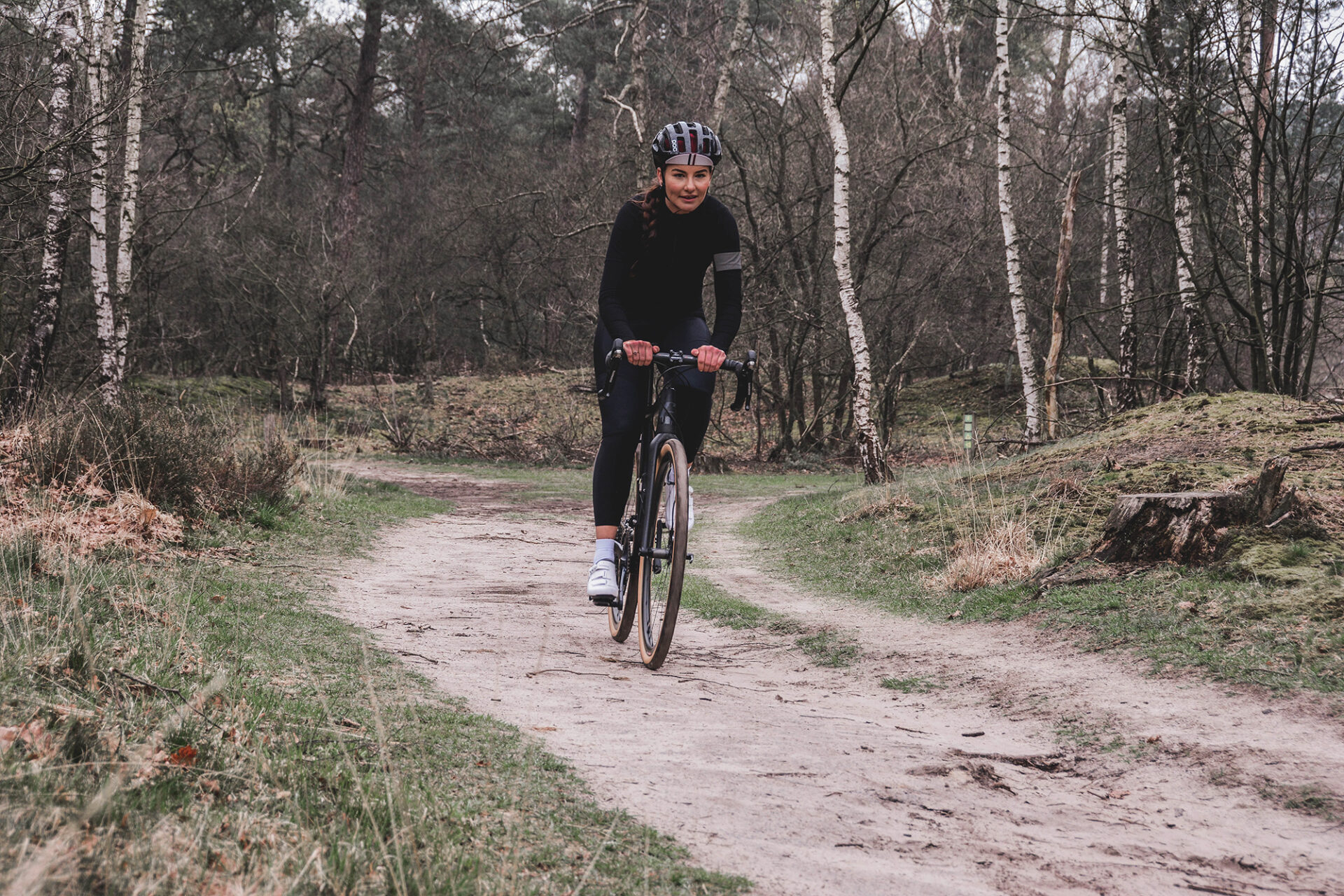 female cyclist on dirt road through aspen trees