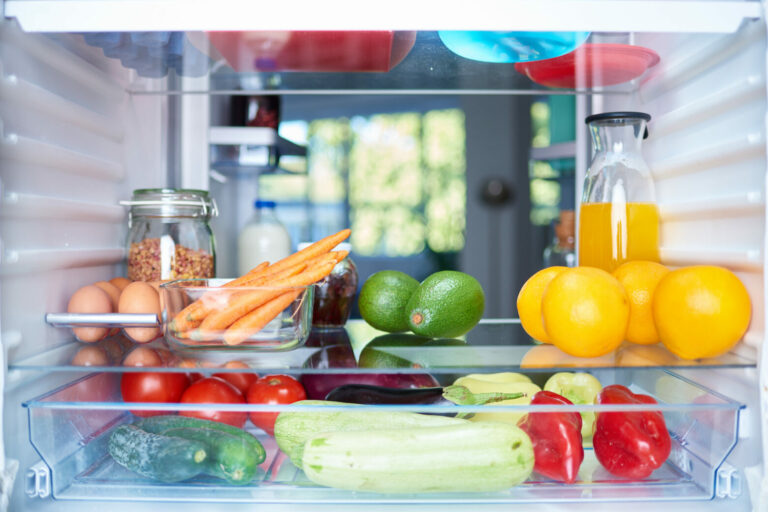 Opened fridge from the inside full of vegetables, fruits and other groceries.