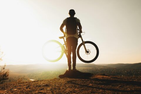 Cyclist on rock edge in sunlight for reframing goal setting perspectives