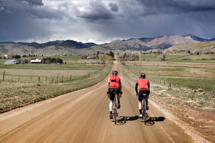 Two cyclists ride into the distance on dirt roads in North Boulder, Colorado.