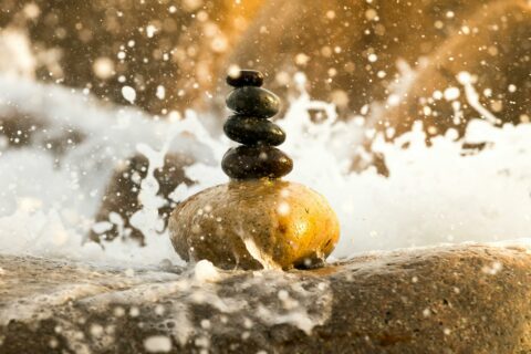 rocks balanced on top of each other as a wave crashes