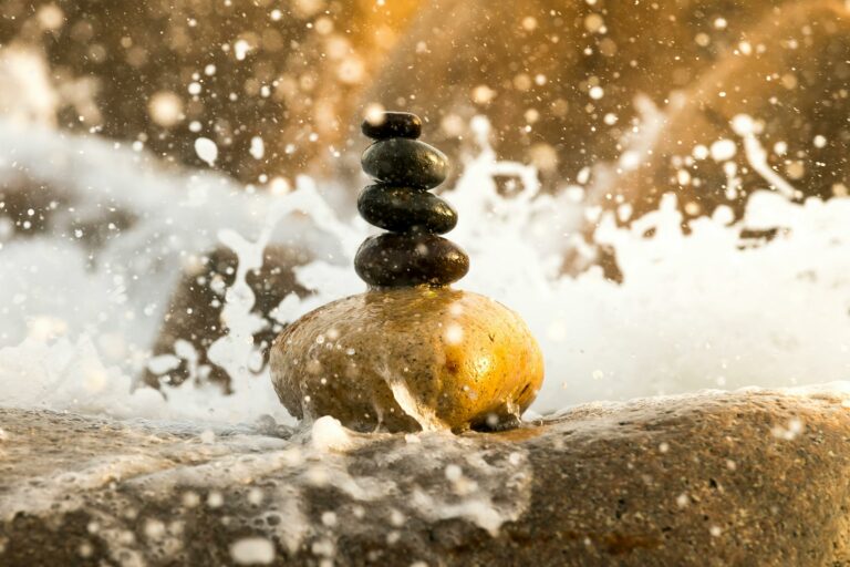 rocks balanced on top of each other as a wave crashes
