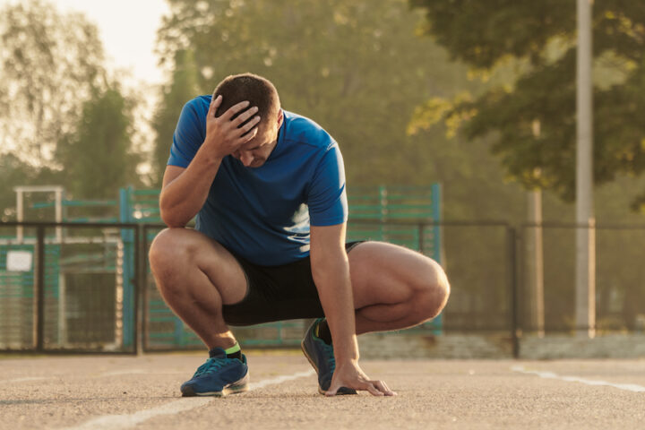a frustrated athlete holds his head after a workout