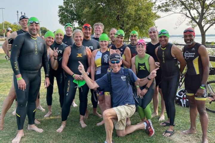 Coach Joe LoPresto and a group of smiling triathletes in their swim gear