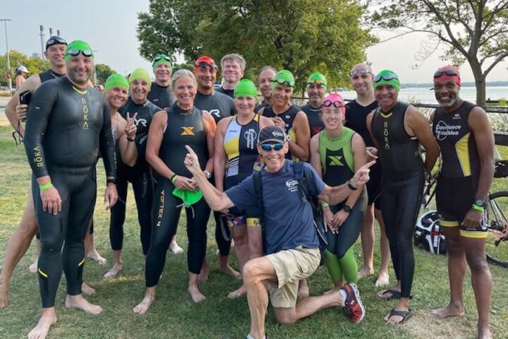 Coach Joe LoPresto and a group of smiling triathletes in their swim gear