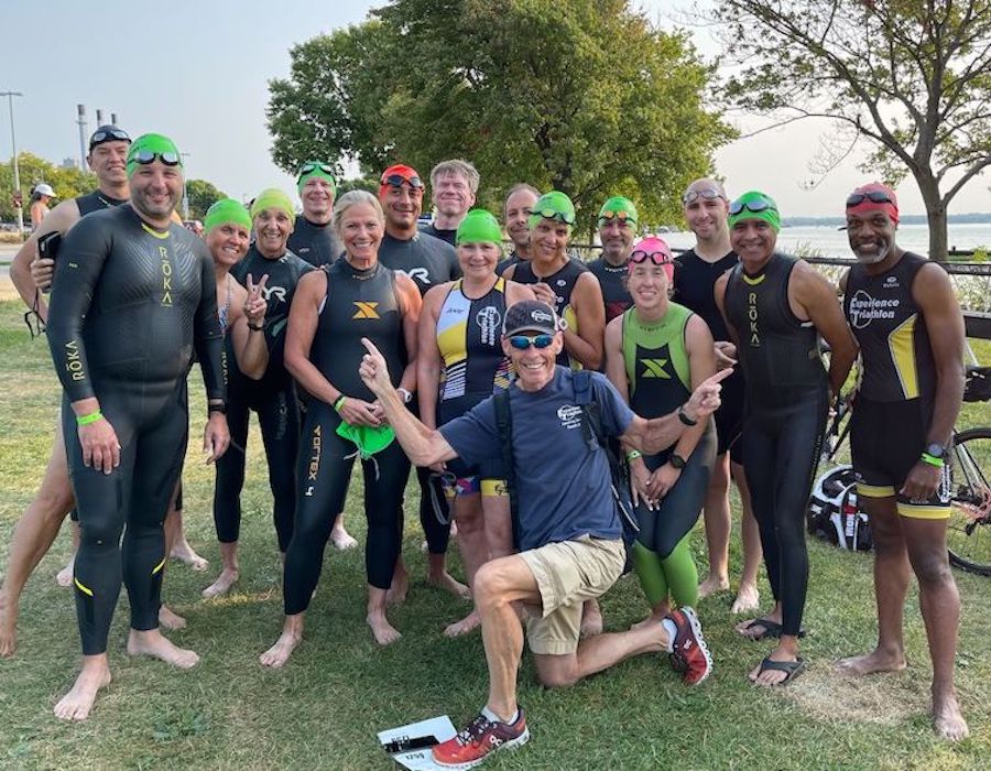 Coach Joe LoPresto and a group of smiling triathletes in their swim gear