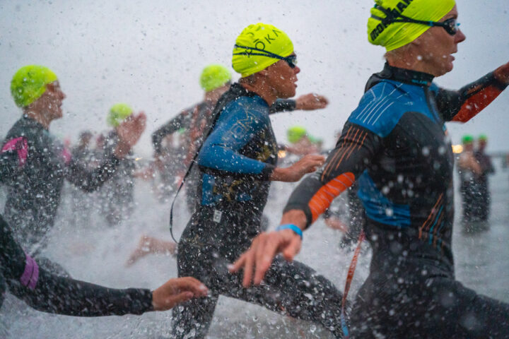 Triathletes running into the water at the swim start