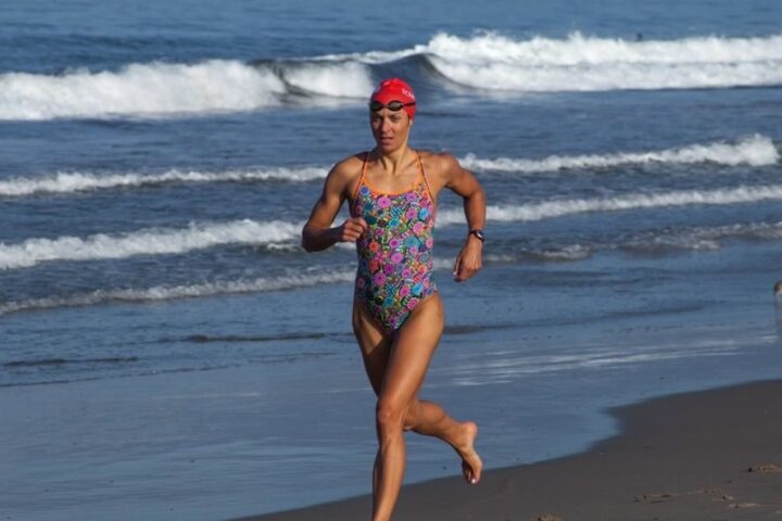 Emma-Kate Lidbury running on the beach in a swimsuit as part of the Tower 26 triathlon training program