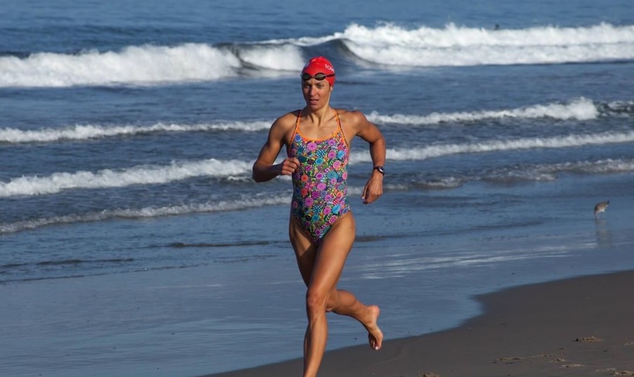 Emma-Kate Lidbury running on the beach in a swimsuit as part of the Tower 26 triathlon training program