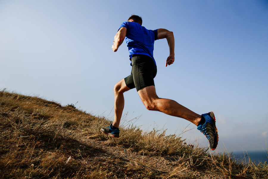 dynamic running uphill on trail male athlete runner side view