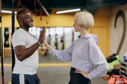 A man and woman high-five in a gym