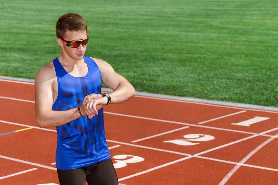 Runner checking his watch on a track