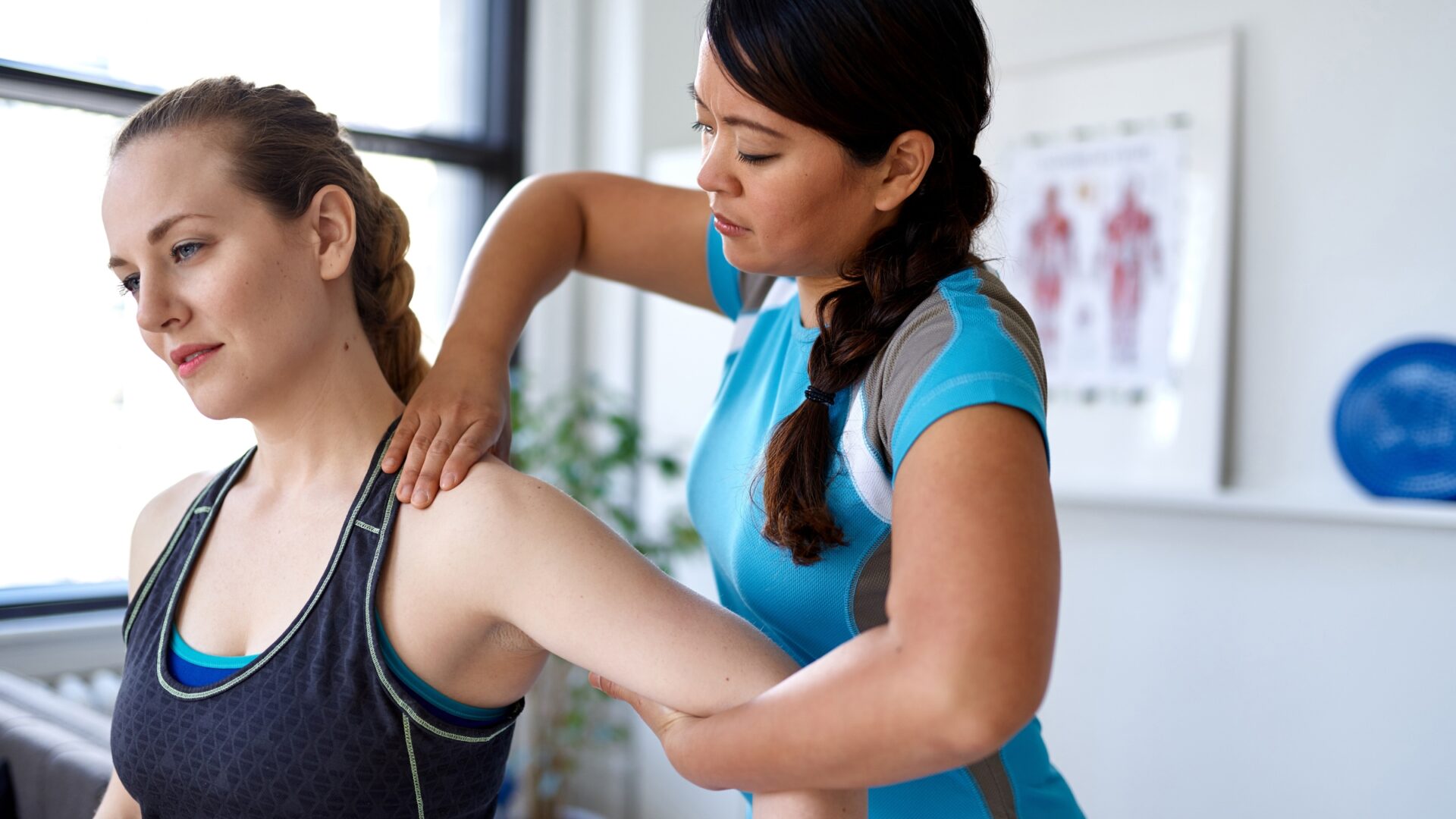 A physical therapist performing manual therapy on her female patient by manipulating her arm