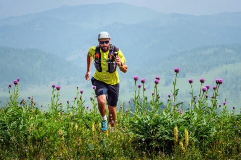 Ultra runner cresting a hill with flowers