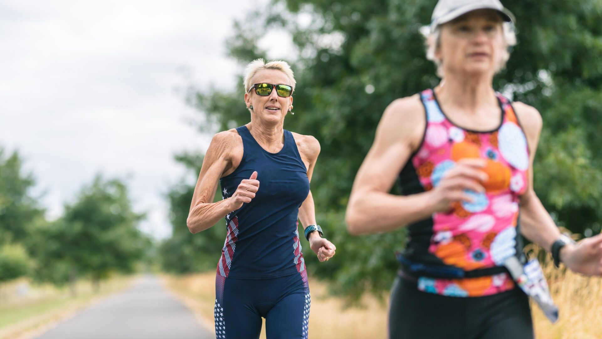 Two older women running down a trail during a triathlon