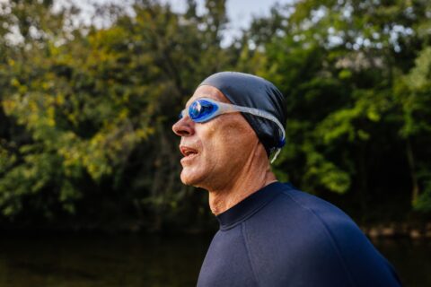 A senior triathlete coming out of swimming in the river, as part of triathlon training.