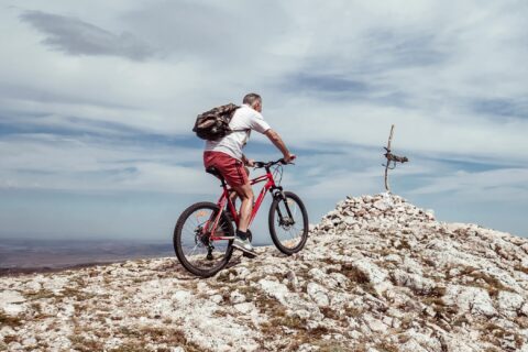 older man reaching a mountain peak while mountain biking