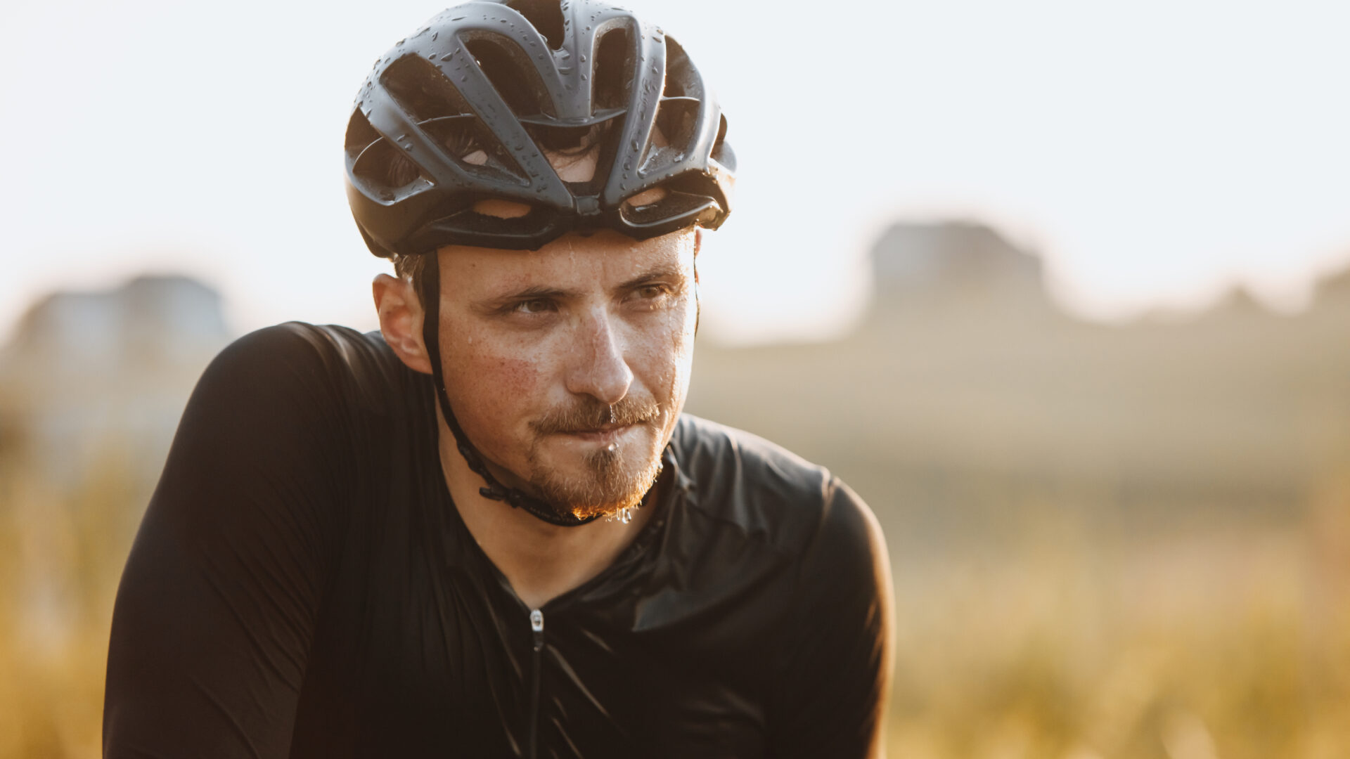 A cyclist pauses in the discomfort of a hot ride to drench himself in water