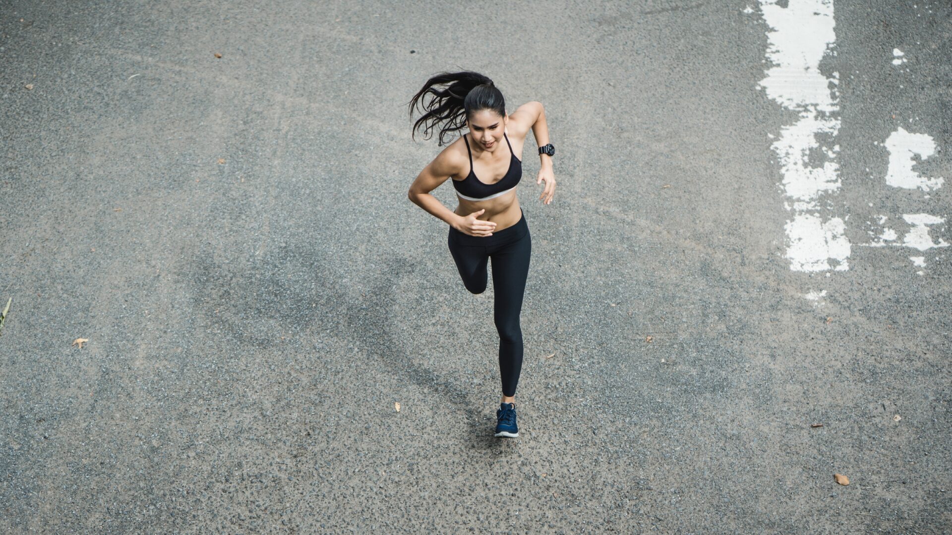 Woman sprinting across asphalt