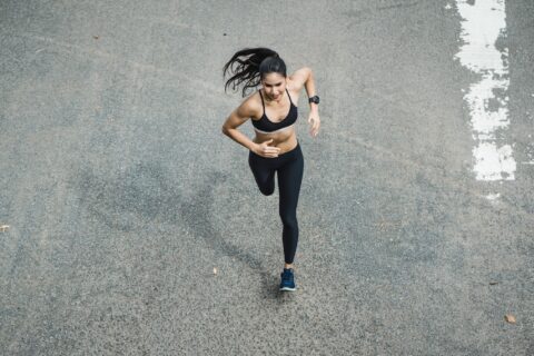 Woman sprinting across asphalt