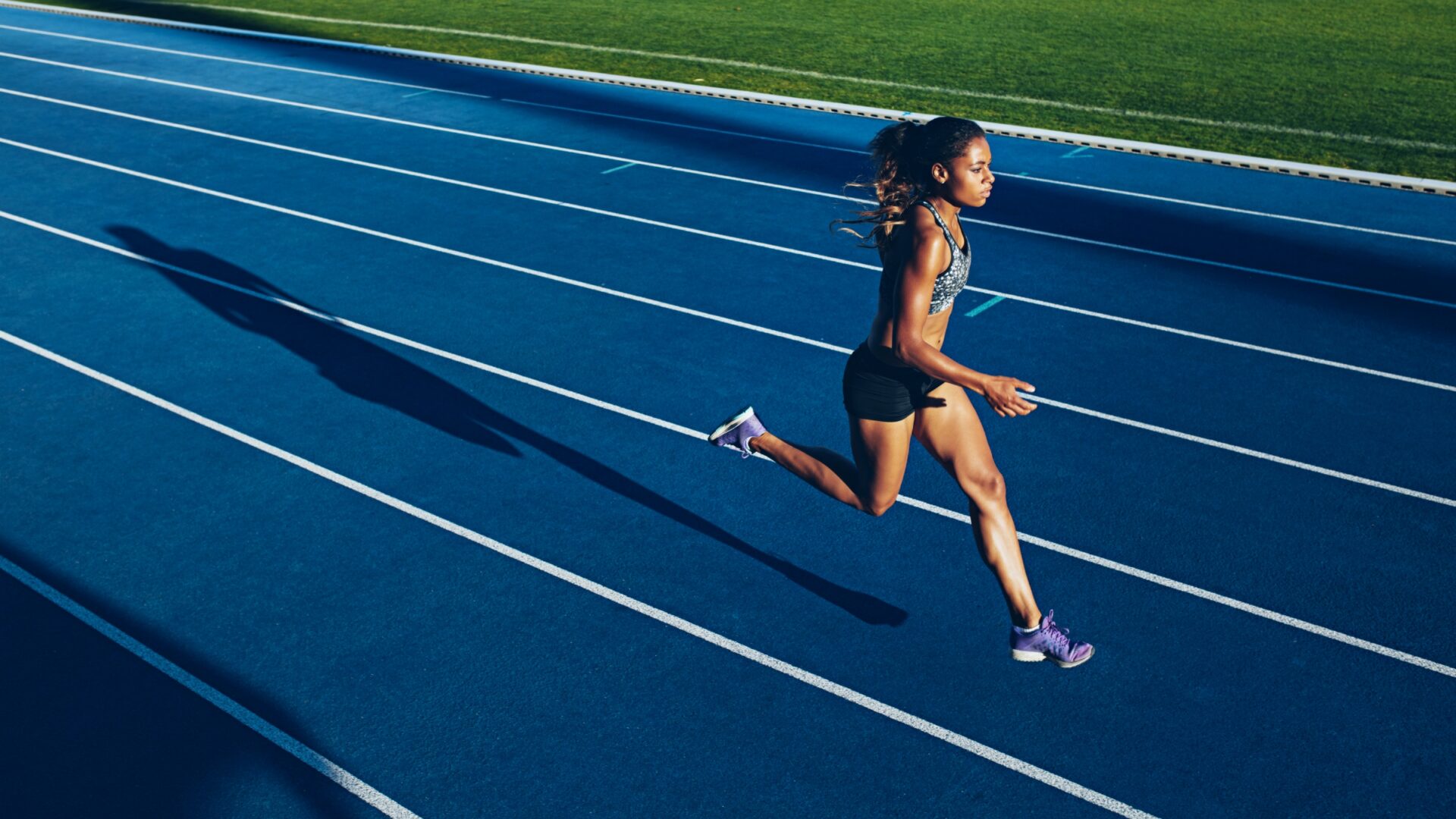 Woman running intervals on a blue outdoor running track