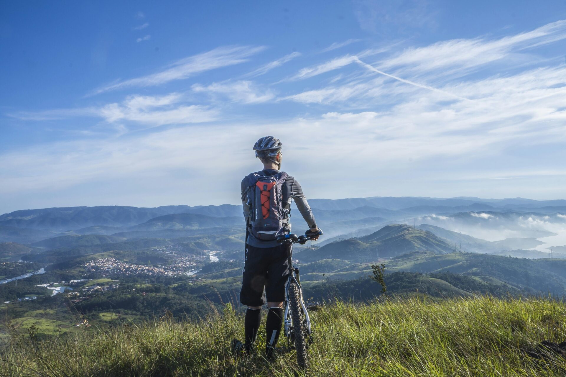 Backpack cyclist overlooking mountains.
