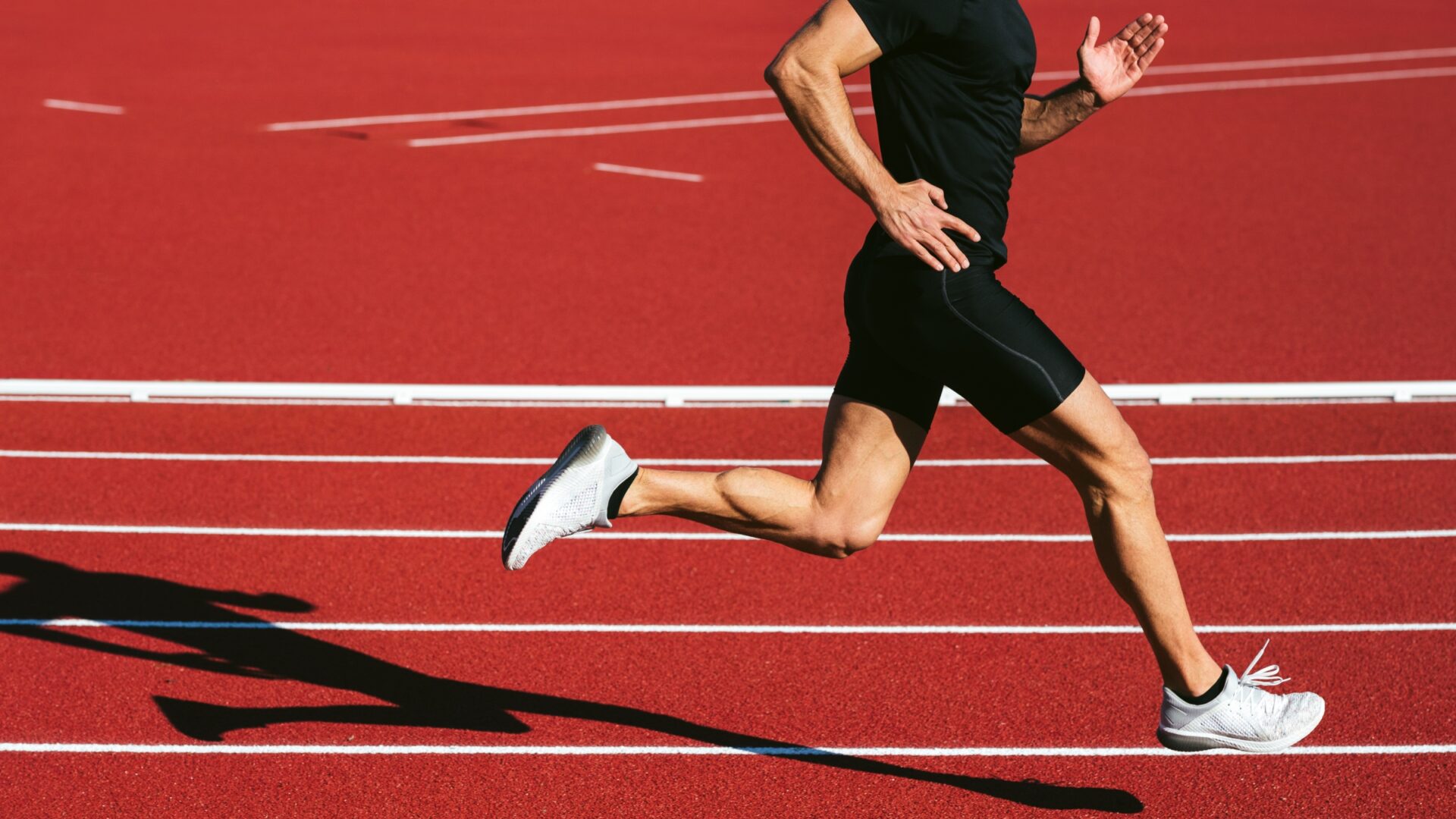 Lower section of a runner sprinting on a red running track
