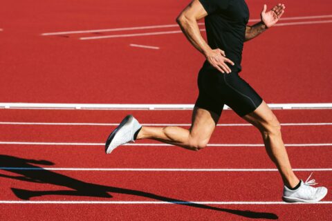 Lower section of a runner sprinting on a red running track