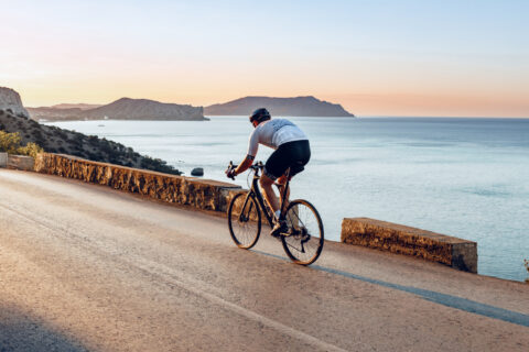 Cyclist riding along the coast at sunset