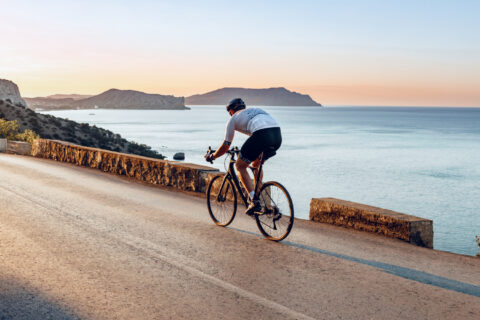 Cyclist riding along the coast at sunset