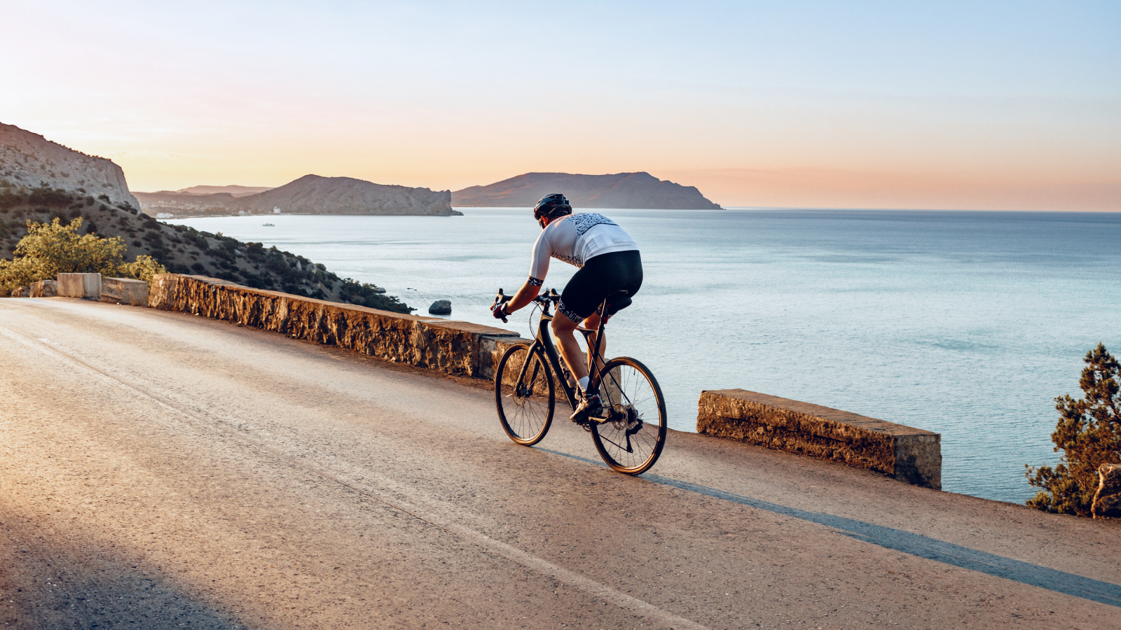 Cyclist riding along the coast at sunset