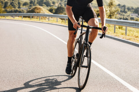 Close-up of lower section of a cyclist climbing up a road