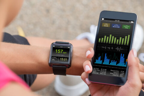 Woman comparing a data set on her phone to her fitness watch.