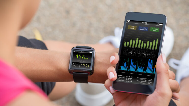Woman comparing a data set on her phone to her fitness watch.