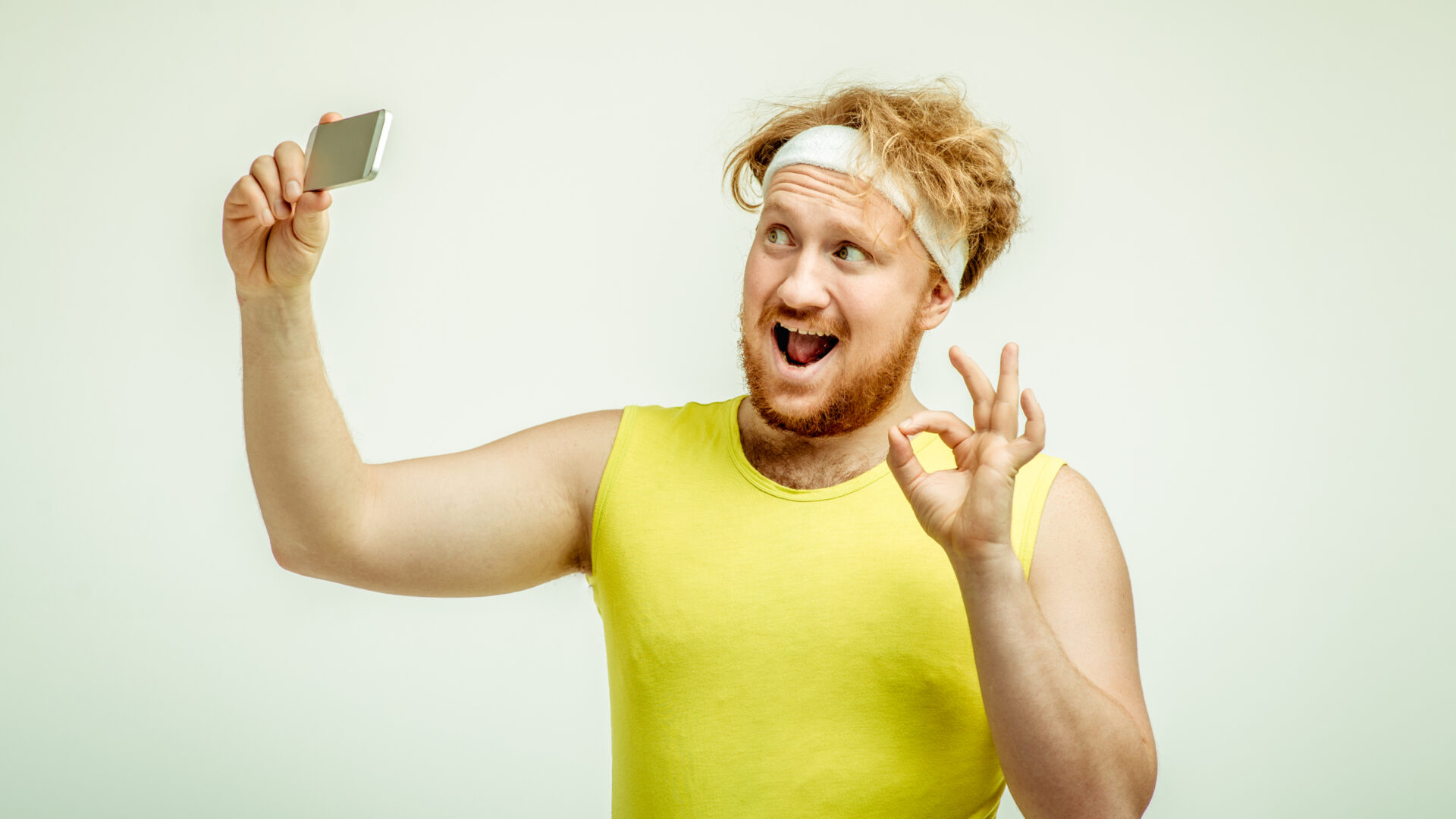 Silly man in a sweat band with messy hair taking a selfie.