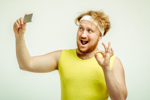 Silly man in a sweat band with messy hair taking a selfie.