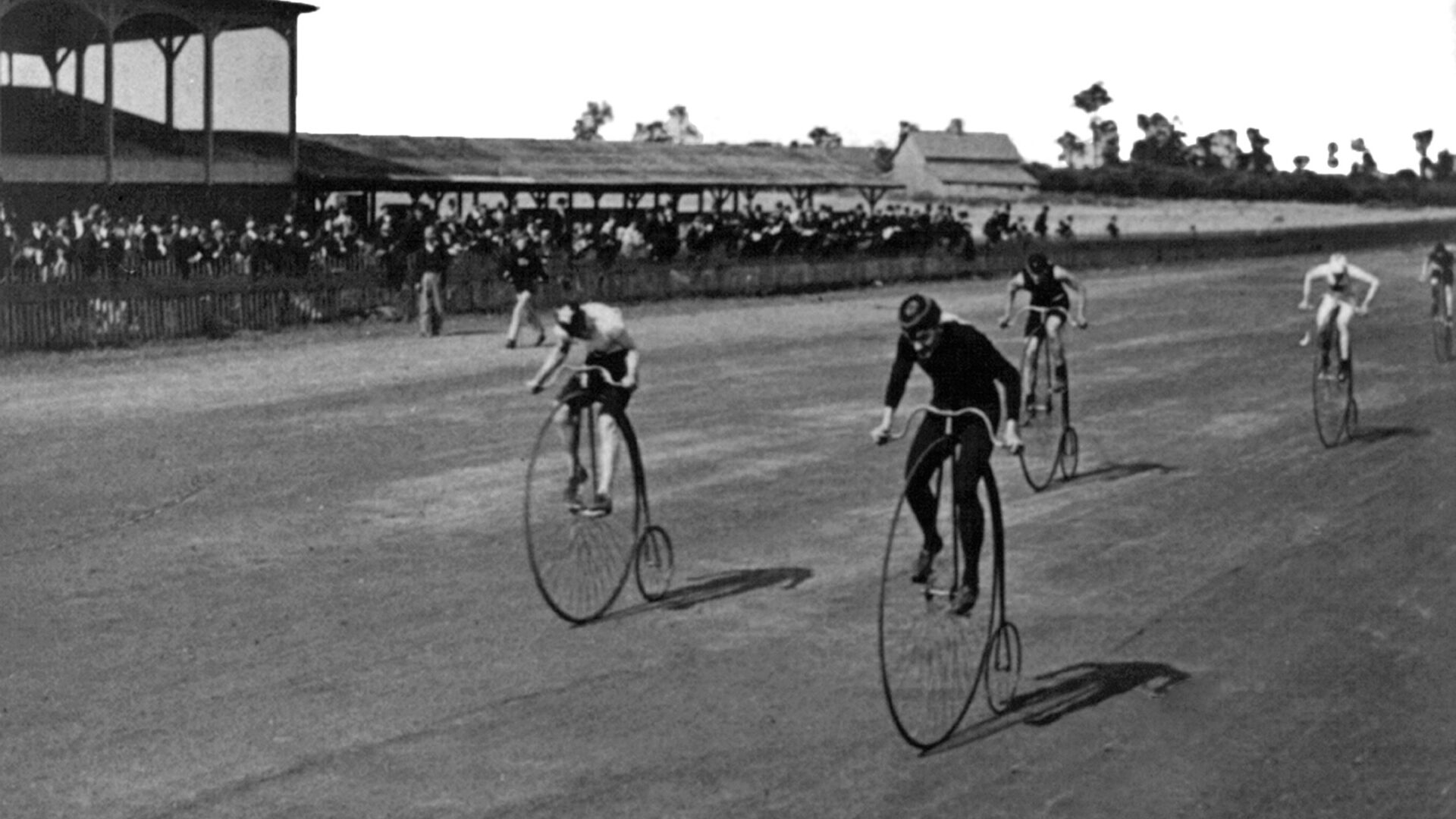 Black and white historical photos of cyclists racing on boneshaker bikes