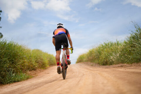 Cyclist riding away from the camera on a gravel road