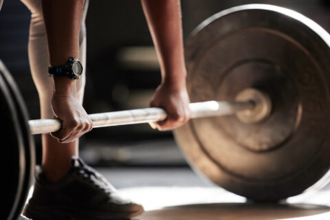 Closeup of a man about to deadlift a barbell