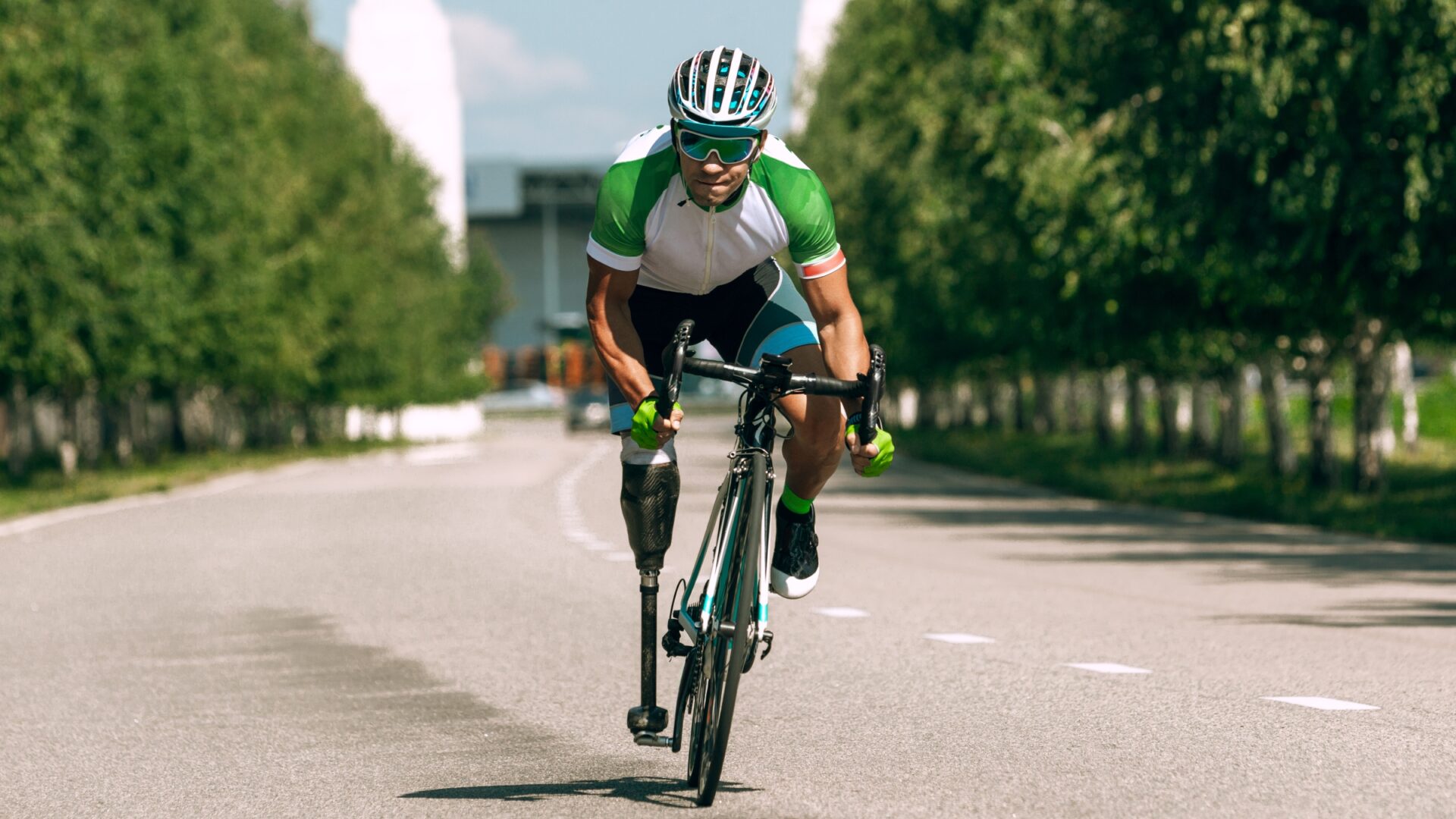 A male cyclist with a prosthetic leg rides out of the saddle toward the camera.