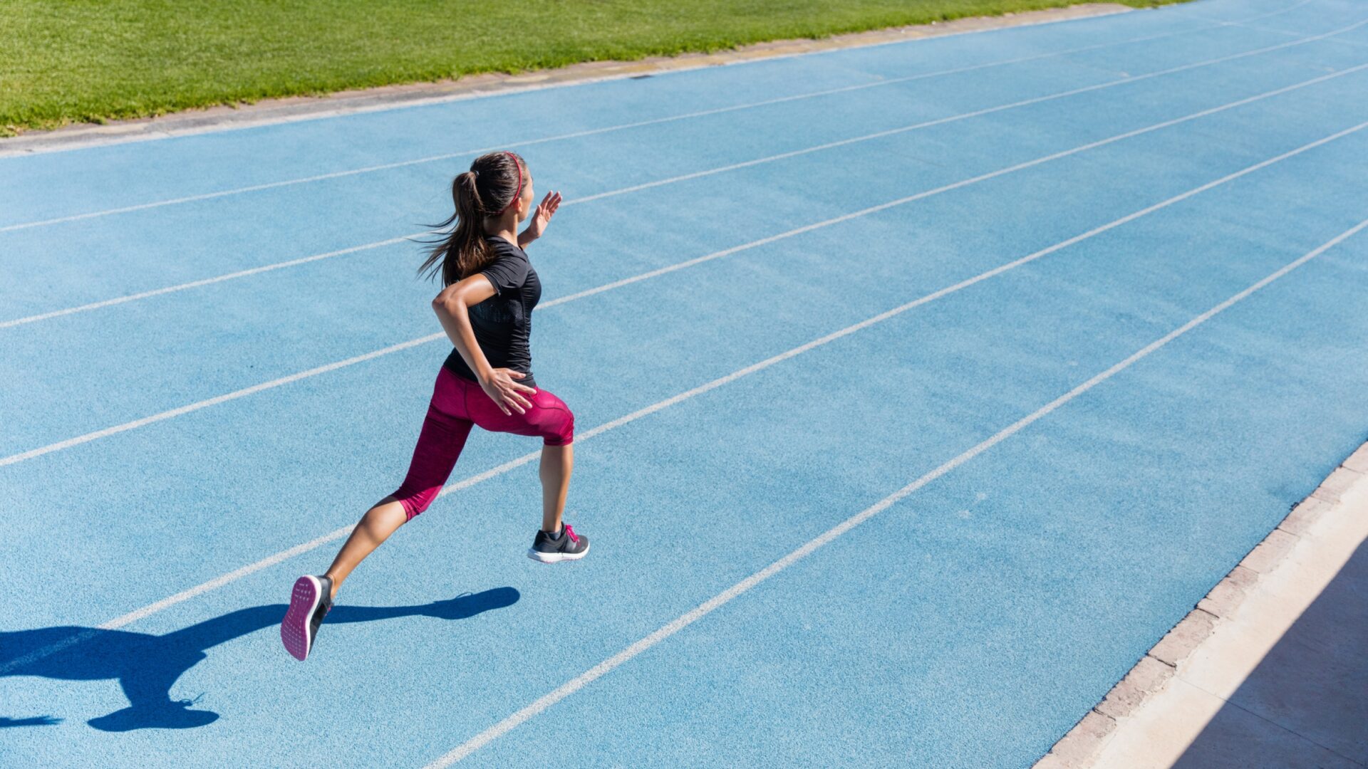 Woman running along a blue outdoor running track