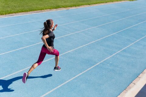 Woman running along a blue outdoor running track