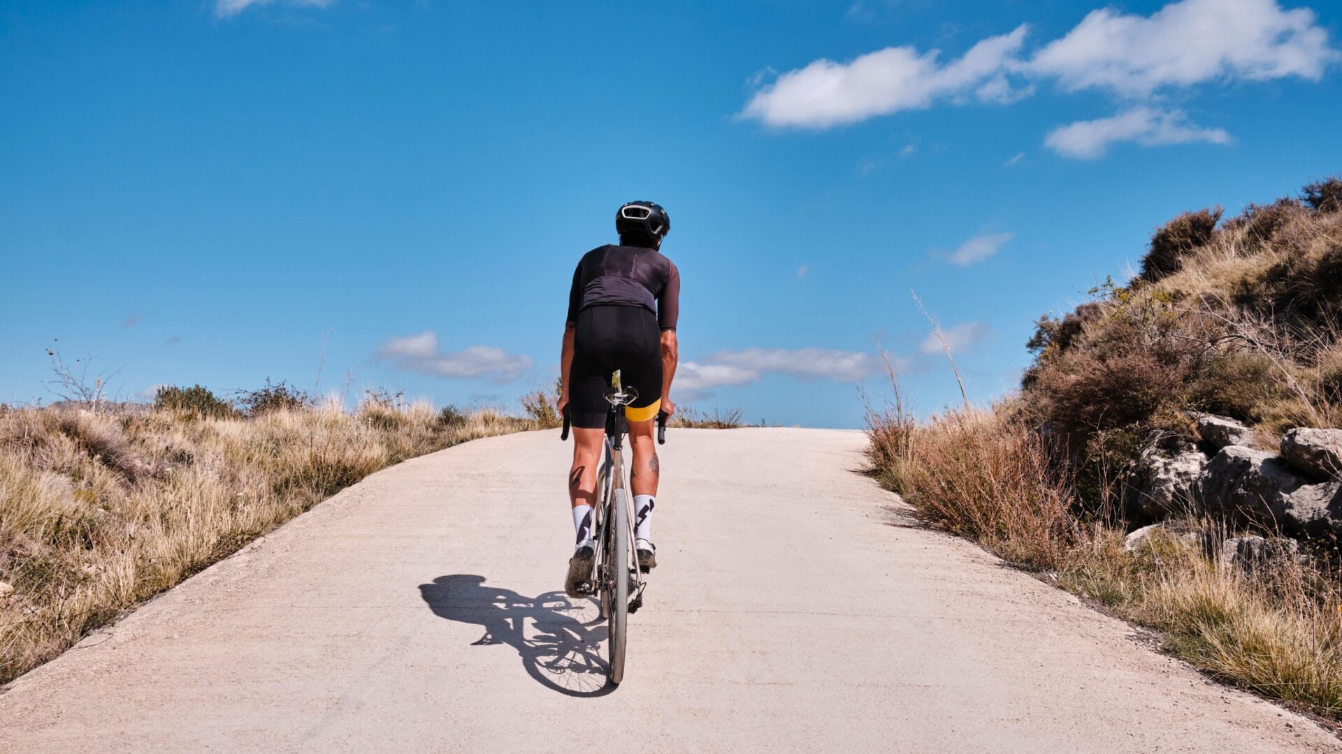 Cyclist summiting a hill with blue sky ahead