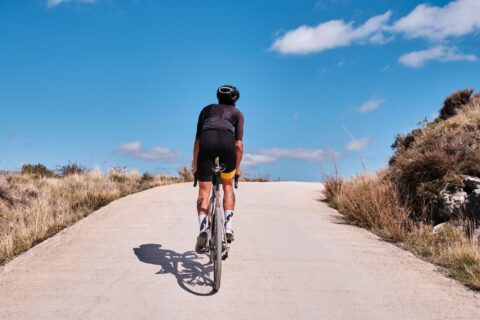 Cyclist summiting a hill with blue sky ahead
