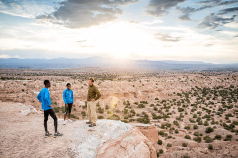 Endurance sports coach Ryan Bolton talks with athletes on a butte overlooking the Arizona desert.